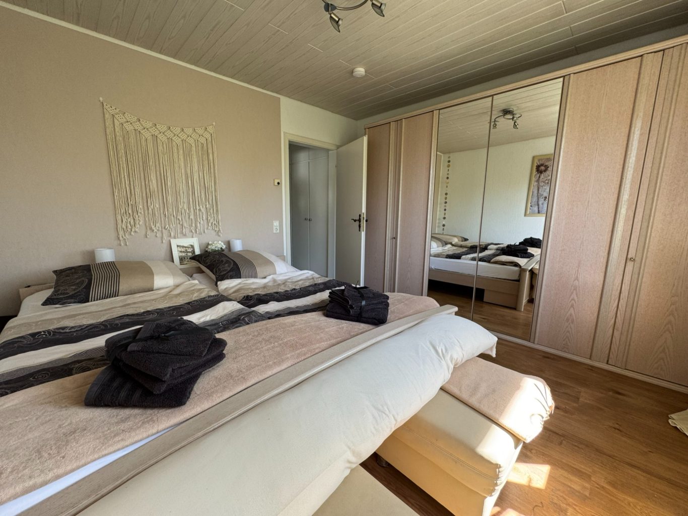 3.60m Spiegelschrank Modernes Schlafzimmer mit zwei Betten, Kleiderschrank und minimalistischer Dekoration.