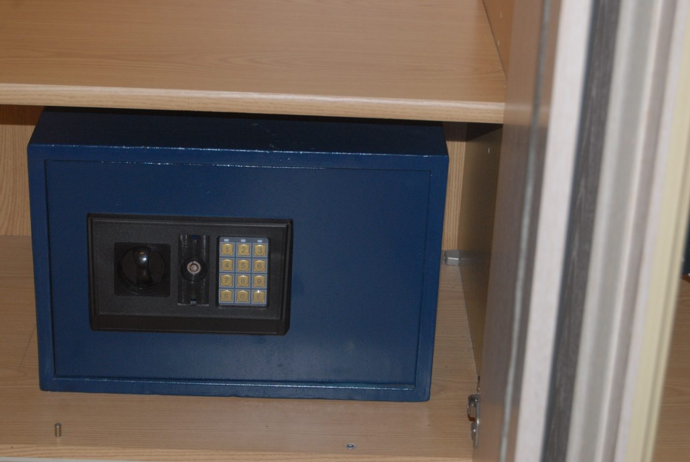 Eingebauter Tresor Blauer Tresor mit Zahlentastatur, eingebaut in ein Regal.