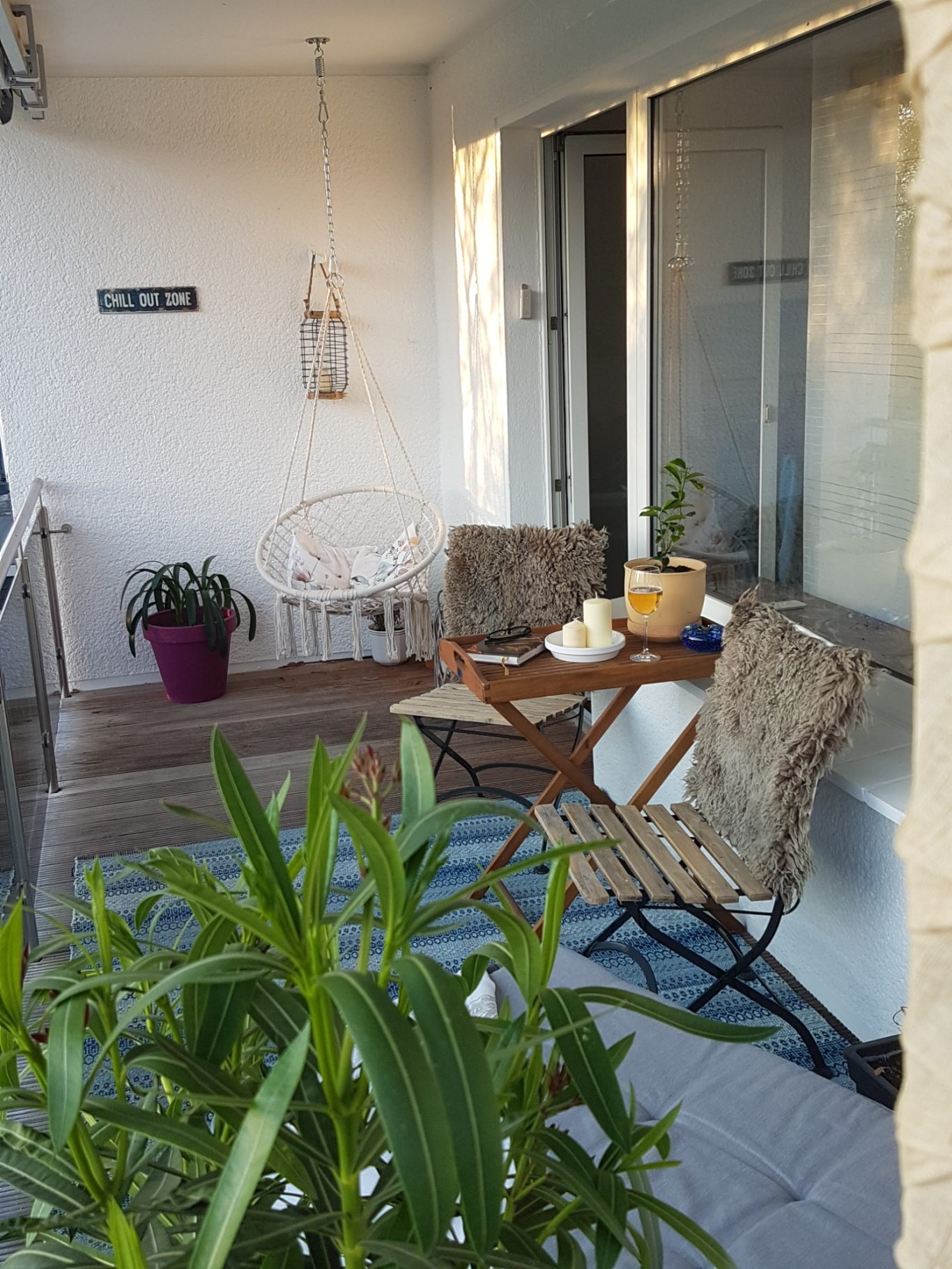 Gemütlicher Balkon mit zwei Stühlen, Tisch und Pflanzen in Töpfen.