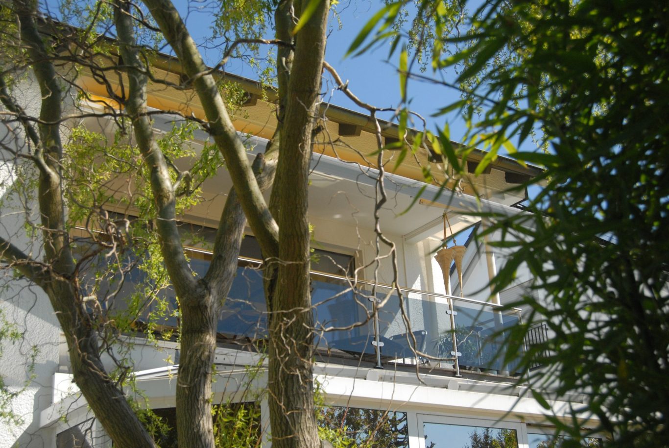 Moderne Architektur eines Hauses umgeben von Bäumen und klarem blauen Himmel.