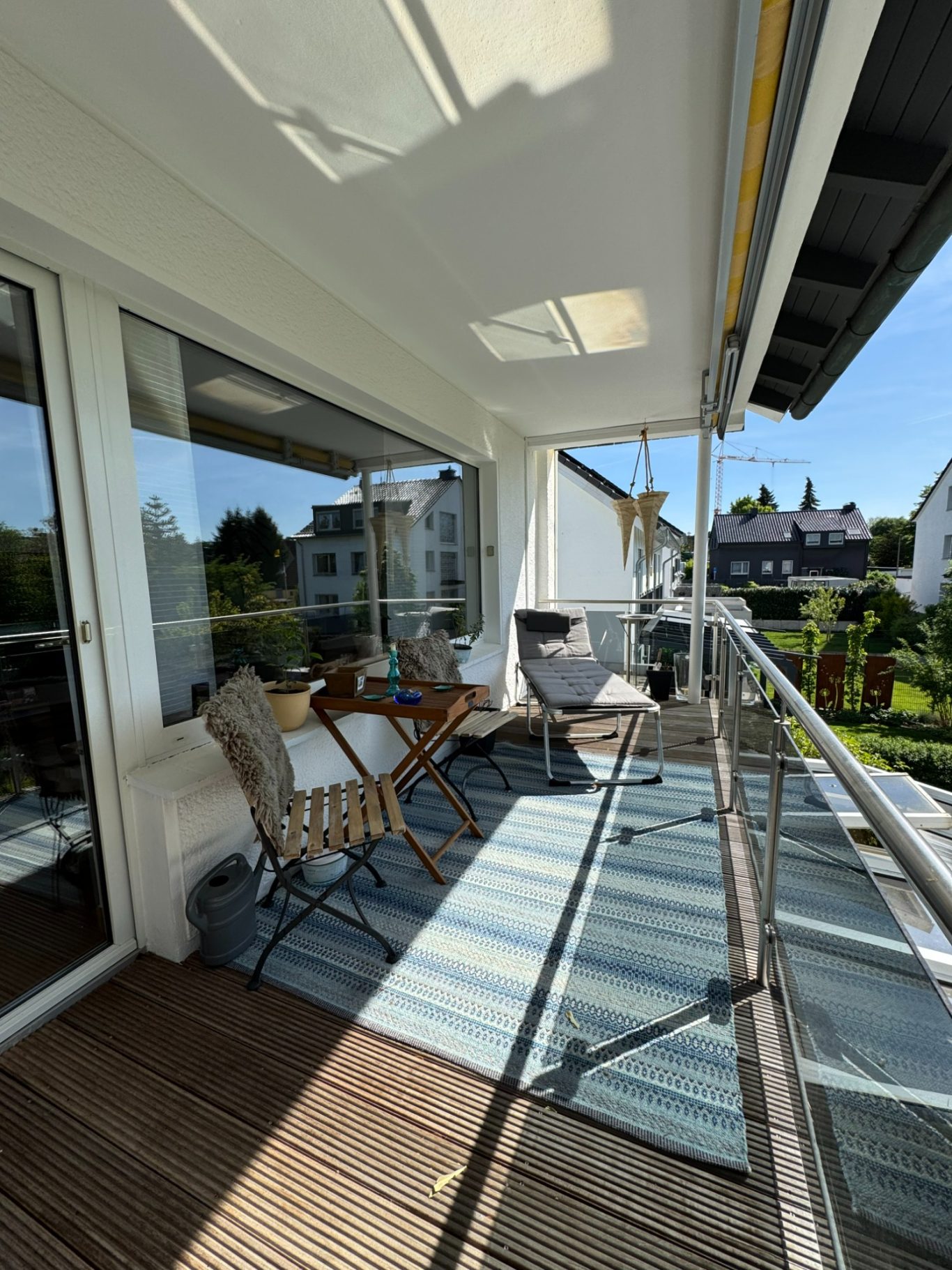 Sonnenbalkon Balkon mit Tisch, Stühlen und Blick auf die Umgebung bei sonnigem Wetter.
