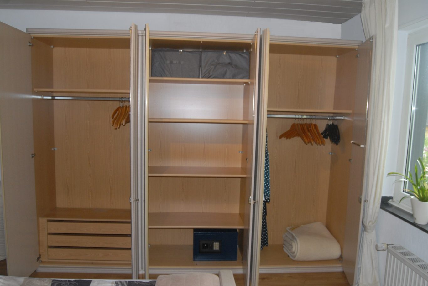 3.60 Kleiderschrank Ein leerer Kleiderschrank mit mehreren Regalen und einer Stange zum Aufhängen von Kleidung.