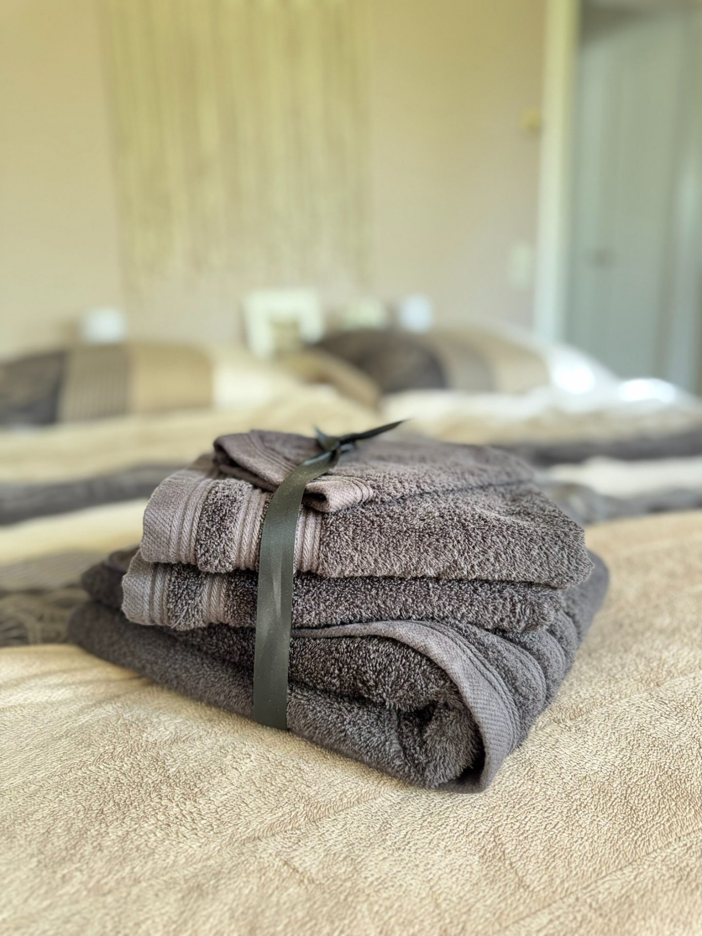 Gepäckte, graue Handtücher auf einem Bett mit neutralen Farben.